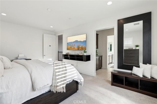 bedroom featuring connected bathroom and light colored carpet