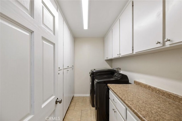 laundry room with cabinets, light tile patterned flooring, and washer and clothes dryer