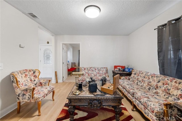 living room with a textured ceiling and light hardwood / wood-style floors