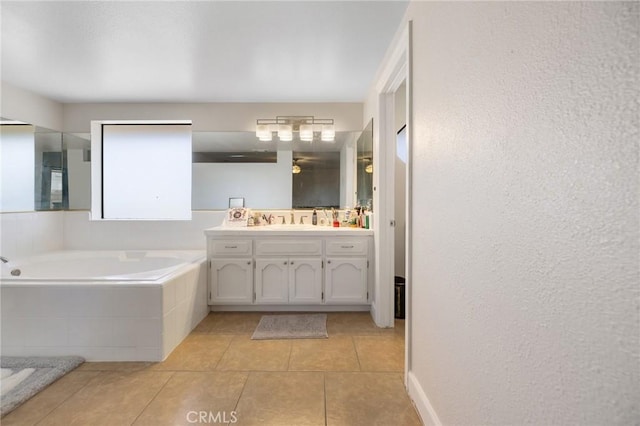 bathroom featuring tile patterned flooring, a relaxing tiled tub, and vanity