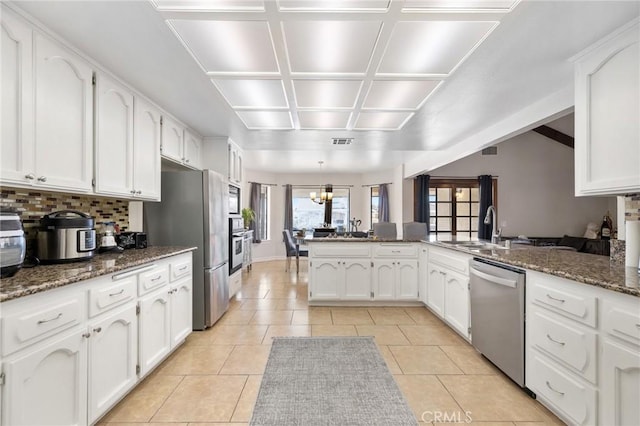 kitchen featuring kitchen peninsula, sink, dark stone countertops, and stainless steel appliances