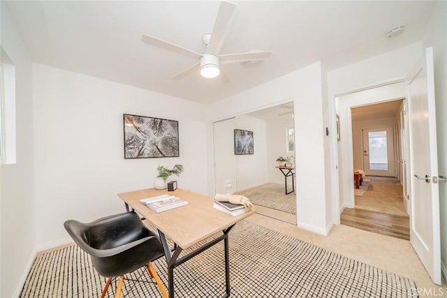 carpeted home office featuring ceiling fan