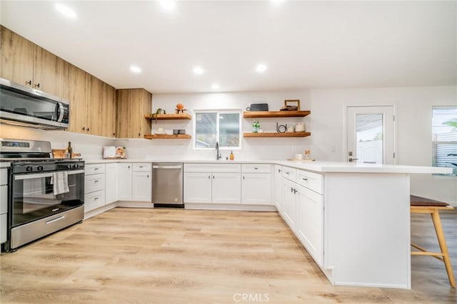 kitchen with sink, white cabinetry, light wood-type flooring, a breakfast bar area, and stainless steel appliances