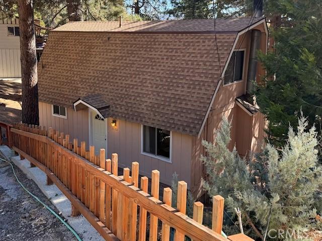 back of property with roof with shingles, fence, and a gambrel roof