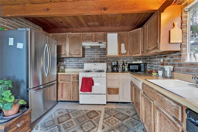 kitchen featuring backsplash, beam ceiling, sink, white range with gas cooktop, and stainless steel fridge