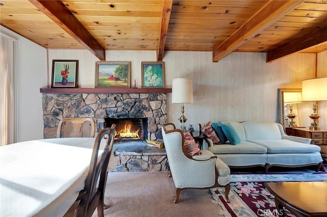 carpeted living room with wooden walls, wooden ceiling, beam ceiling, and a stone fireplace