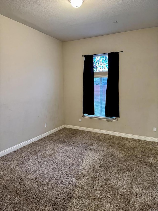 carpeted empty room with a textured ceiling