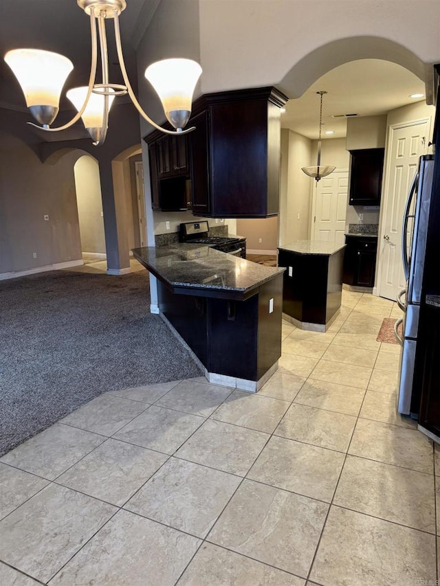 kitchen with stainless steel gas range oven, fridge, a notable chandelier, a breakfast bar, and a center island