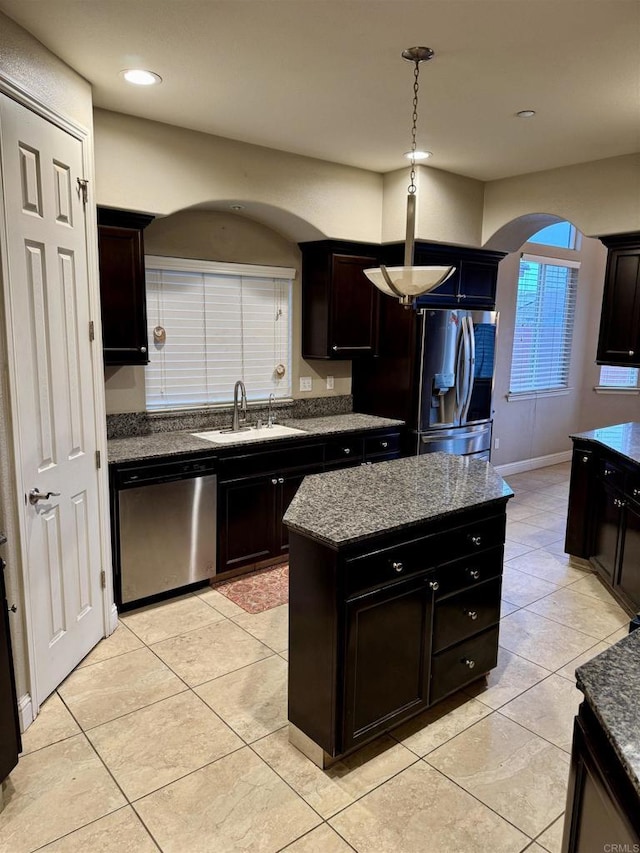 kitchen with a center island, stainless steel appliances, sink, light tile patterned floors, and dark brown cabinets