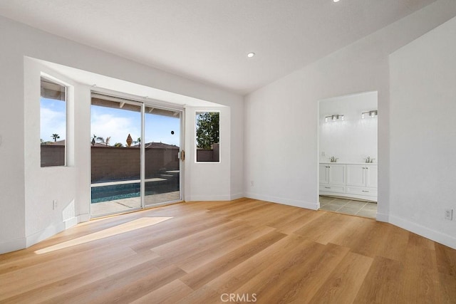 unfurnished room with vaulted ceiling and light wood-type flooring