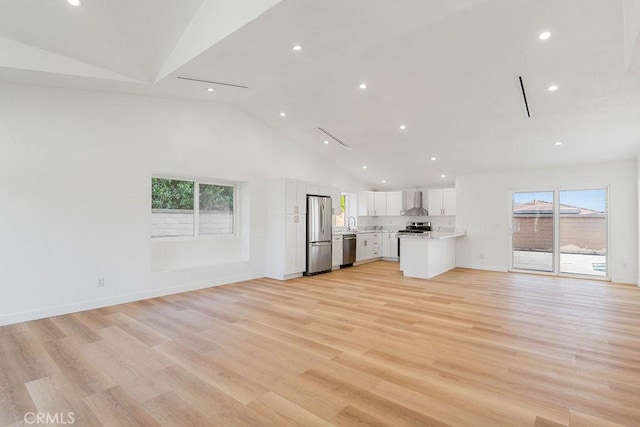 unfurnished living room featuring high vaulted ceiling, a wealth of natural light, and light wood-type flooring