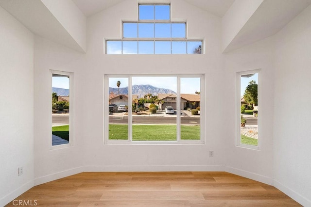 spare room featuring a mountain view, light hardwood / wood-style flooring, and a towering ceiling