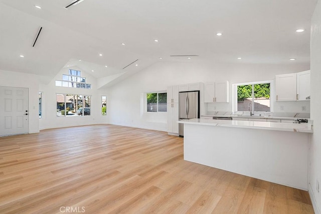 kitchen featuring high vaulted ceiling, white cabinets, and light wood-type flooring