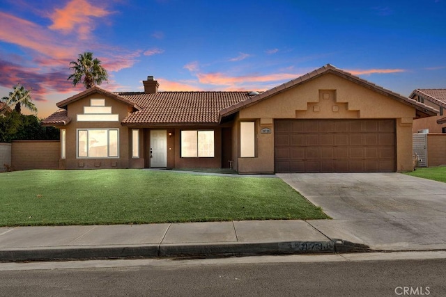 mediterranean / spanish-style house featuring a garage and a yard