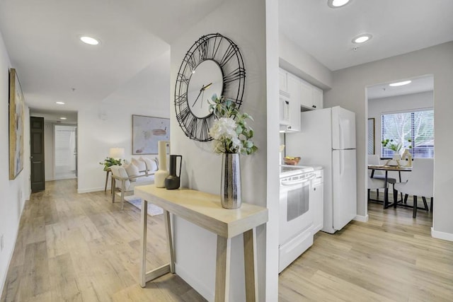 kitchen with white appliances, light hardwood / wood-style flooring, and white cabinets