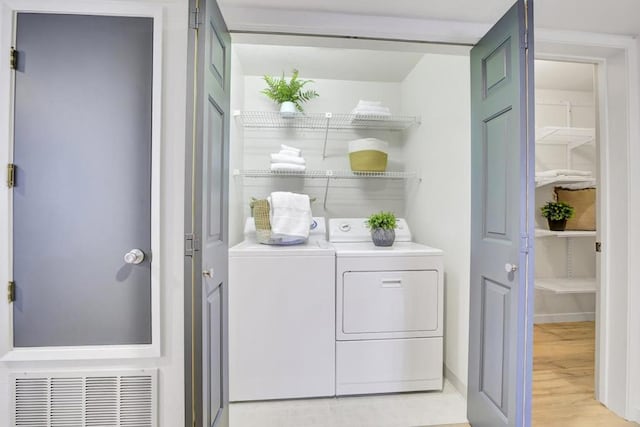 washroom with washing machine and dryer and light hardwood / wood-style floors