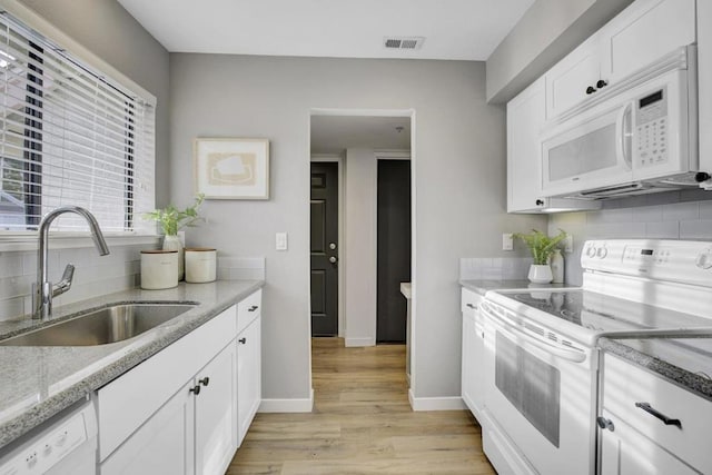 kitchen with sink, white appliances, backsplash, white cabinets, and light wood-type flooring