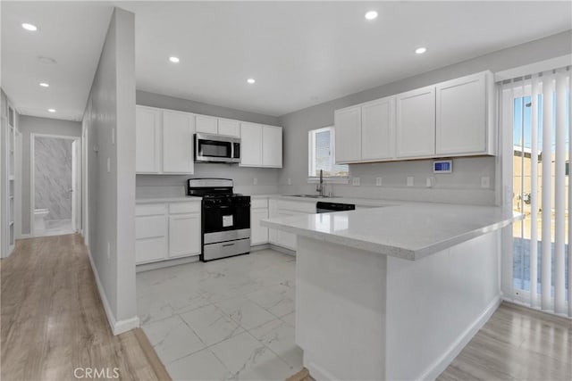 kitchen featuring kitchen peninsula, sink, plenty of natural light, stainless steel appliances, and white cabinets