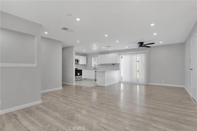 unfurnished living room featuring ceiling fan, sink, and light wood-type flooring