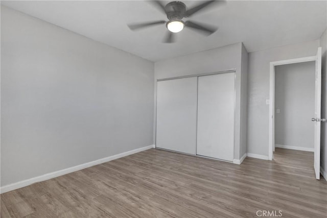 unfurnished bedroom featuring ceiling fan, a closet, and light wood-type flooring