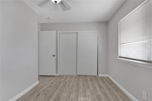 unfurnished bedroom featuring ceiling fan, light hardwood / wood-style floors, and a closet