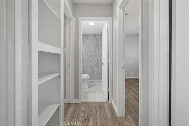 hallway featuring tile walls and light hardwood / wood-style flooring