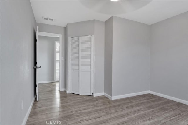 unfurnished bedroom with light hardwood / wood-style floors, a closet, and ceiling fan