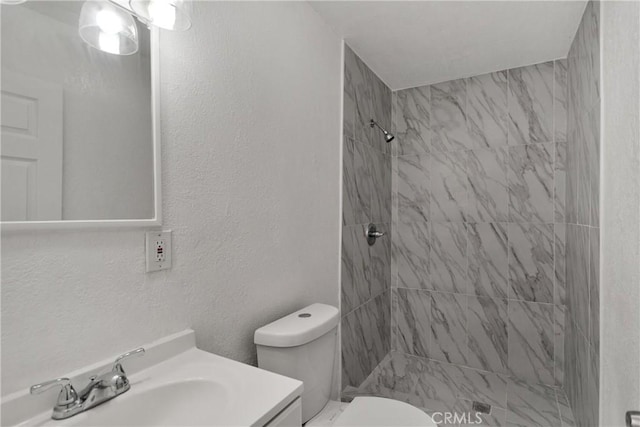 bathroom featuring toilet, vanity, and tiled shower