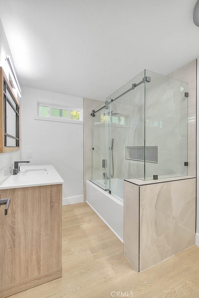 bathroom with hardwood / wood-style floors, shower / bath combination with glass door, and vanity