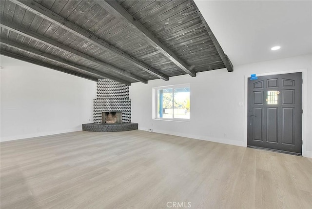 unfurnished living room with light wood-type flooring, wood ceiling, a fireplace, and lofted ceiling with beams