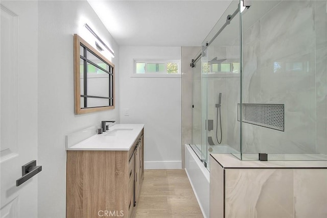 bathroom with combined bath / shower with glass door, hardwood / wood-style flooring, and vanity