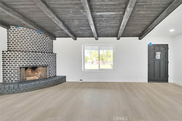 unfurnished living room with wooden ceiling, a fireplace, beamed ceiling, and light hardwood / wood-style floors