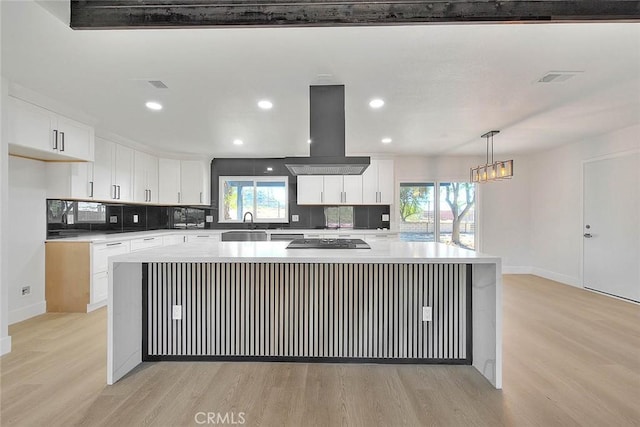 kitchen with island exhaust hood, white cabinets, hanging light fixtures, a kitchen island, and light hardwood / wood-style flooring