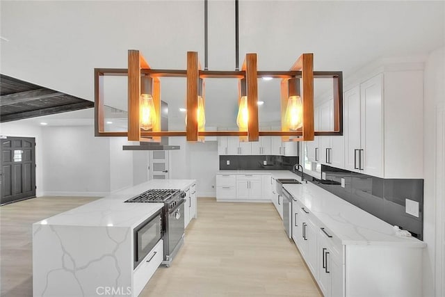 kitchen with black range with gas stovetop, white cabinets, backsplash, and light stone counters