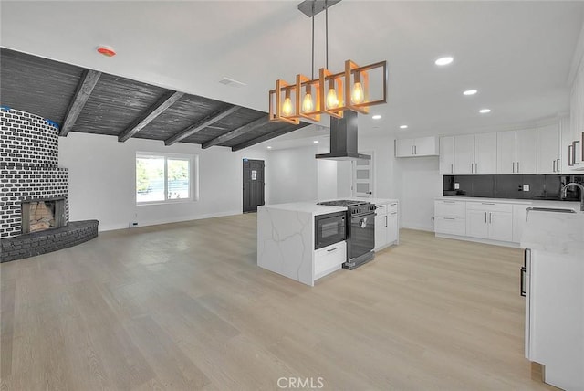 kitchen featuring white cabinets, exhaust hood, light stone countertops, and gas stove