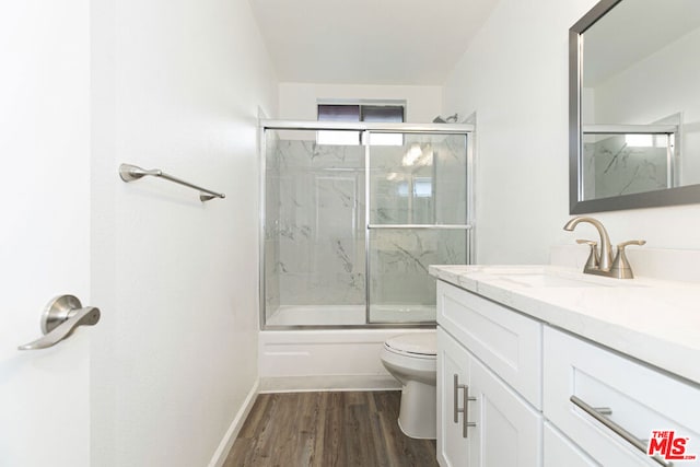 full bathroom with wood-type flooring, vanity, toilet, and bath / shower combo with glass door