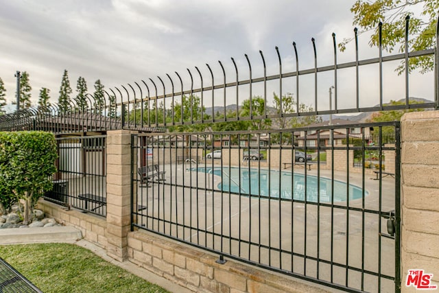 view of gate with a patio area and a community pool