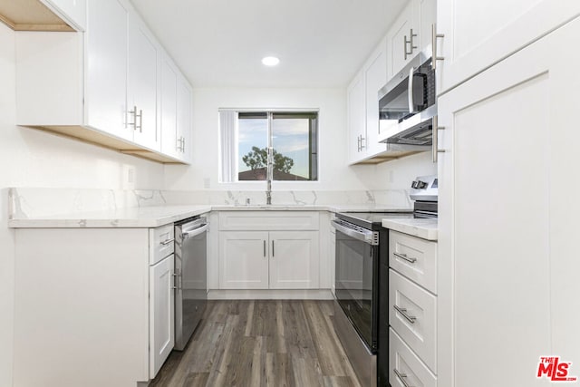 kitchen featuring white cabinets, light stone countertops, stainless steel appliances, and dark wood-type flooring