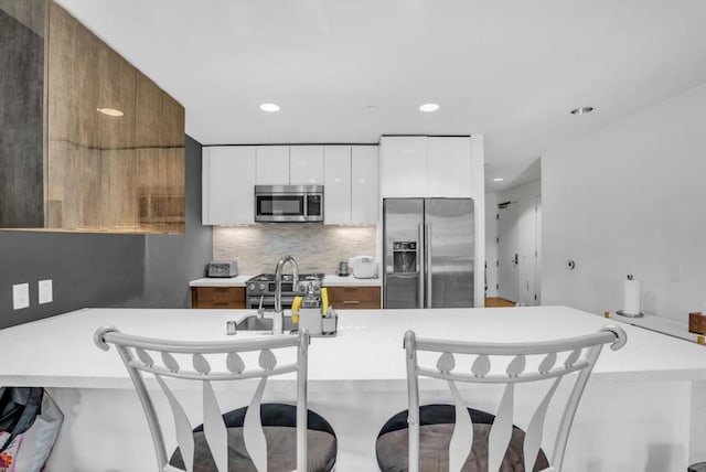 kitchen featuring backsplash, white cabinetry, appliances with stainless steel finishes, and sink