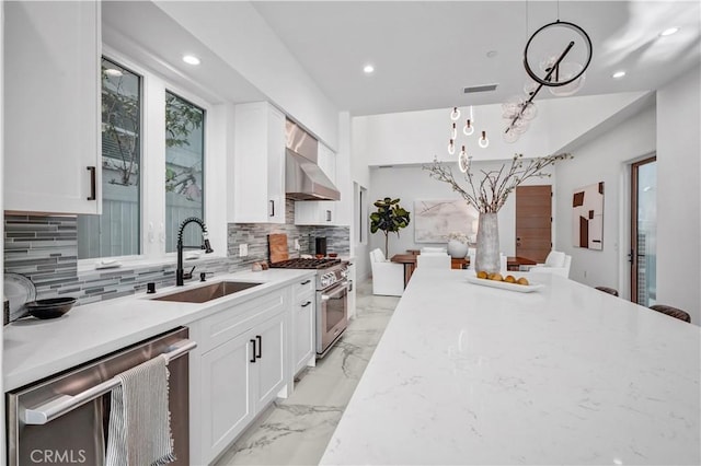 kitchen with decorative light fixtures, white cabinets, appliances with stainless steel finishes, and sink