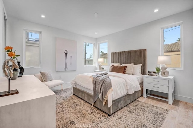 bedroom with light hardwood / wood-style floors and multiple windows