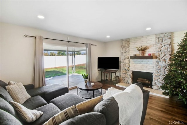 living room featuring a stone fireplace and dark hardwood / wood-style flooring