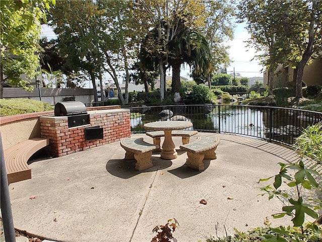 view of patio / terrace featuring exterior kitchen, a grill, and a water view