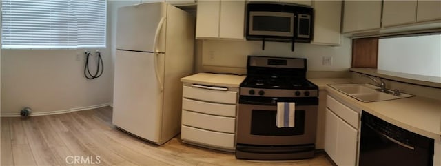 kitchen featuring appliances with stainless steel finishes, white cabinets, light hardwood / wood-style flooring, and sink