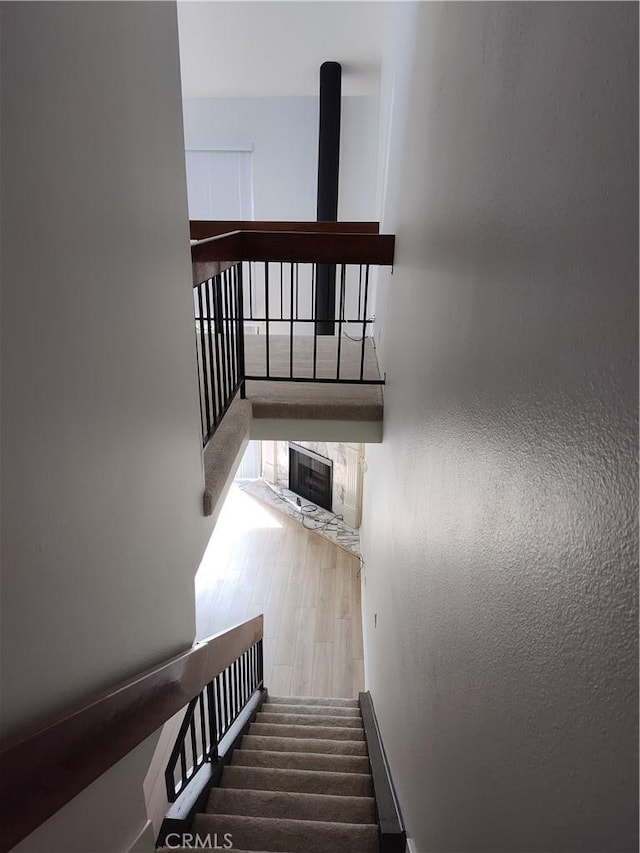 staircase featuring hardwood / wood-style flooring and a fireplace