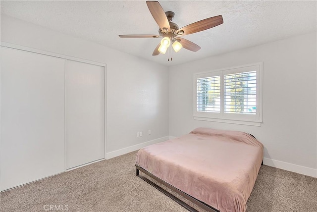 carpeted bedroom featuring ceiling fan, a textured ceiling, and a closet