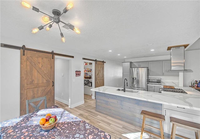 kitchen featuring a barn door, kitchen peninsula, sink, gray cabinetry, and stainless steel appliances