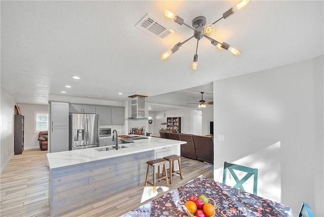 kitchen featuring appliances with stainless steel finishes, light hardwood / wood-style flooring, sink, gray cabinetry, and a breakfast bar area