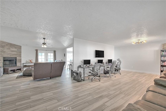 living room featuring a textured ceiling, ceiling fan, french doors, and a tile fireplace