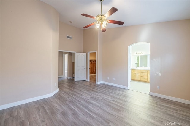 spare room with ceiling fan, a high ceiling, and light hardwood / wood-style floors